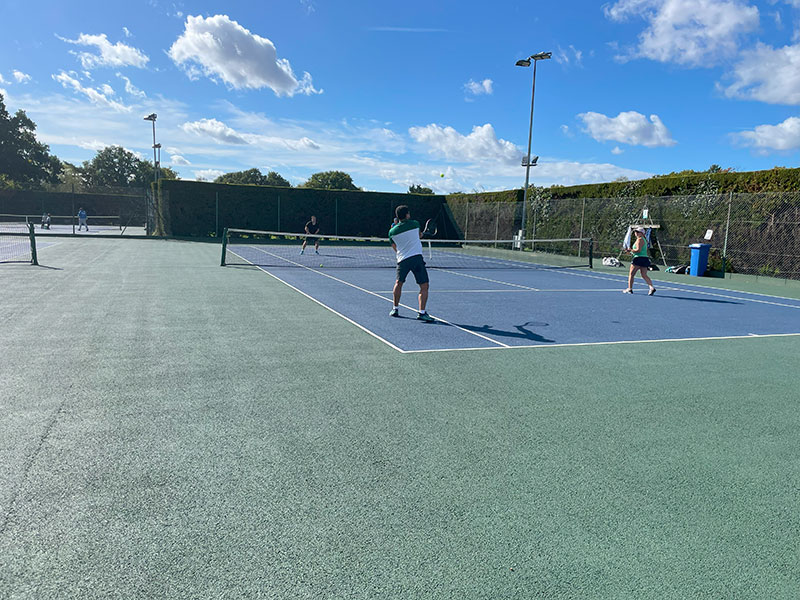 Competitive tennis match being played on all weather courts